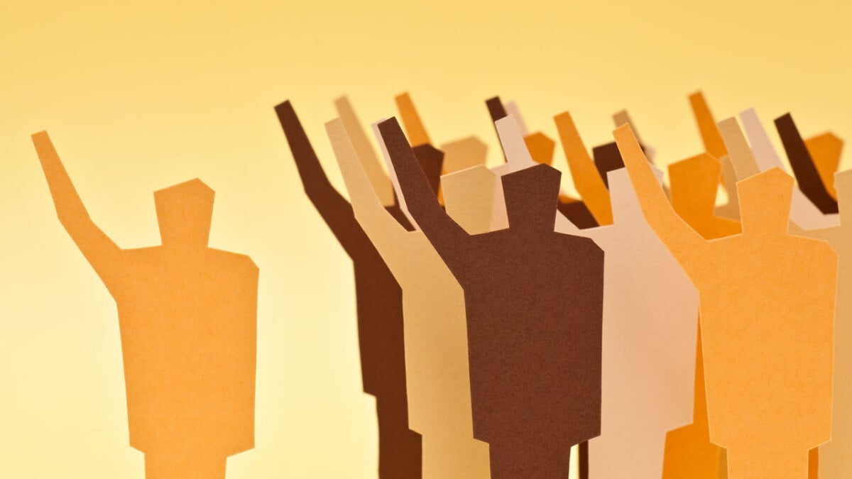 Consensus Theory: Definition & Examples 1 a group of figure outlines with their one arm raised and a leader with their arm raised.