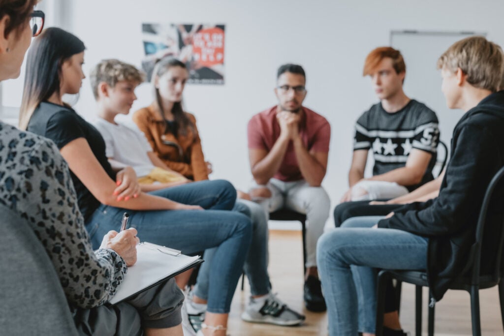 What Is a Focus Group? 1 a focus group of people sat on chairs in a circle. one person is making notes on a clipboard.