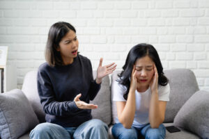Toxic Friendship: How to Deal with Toxic Friends 11 two women arguing on a sofa, one is shouting while the other has head in her hands looking frustrated.
