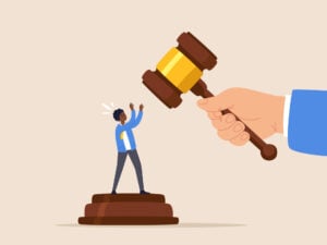 Value Free in Sociology 7 a person stood underneath a judges gavel placing their hands up to symbolise no value judgements being made